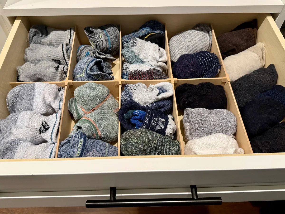 A socks drawer fitted with an Object Containment Device: rolled socks sorted into nine compartments, two rows of four and one long compartment down the right side